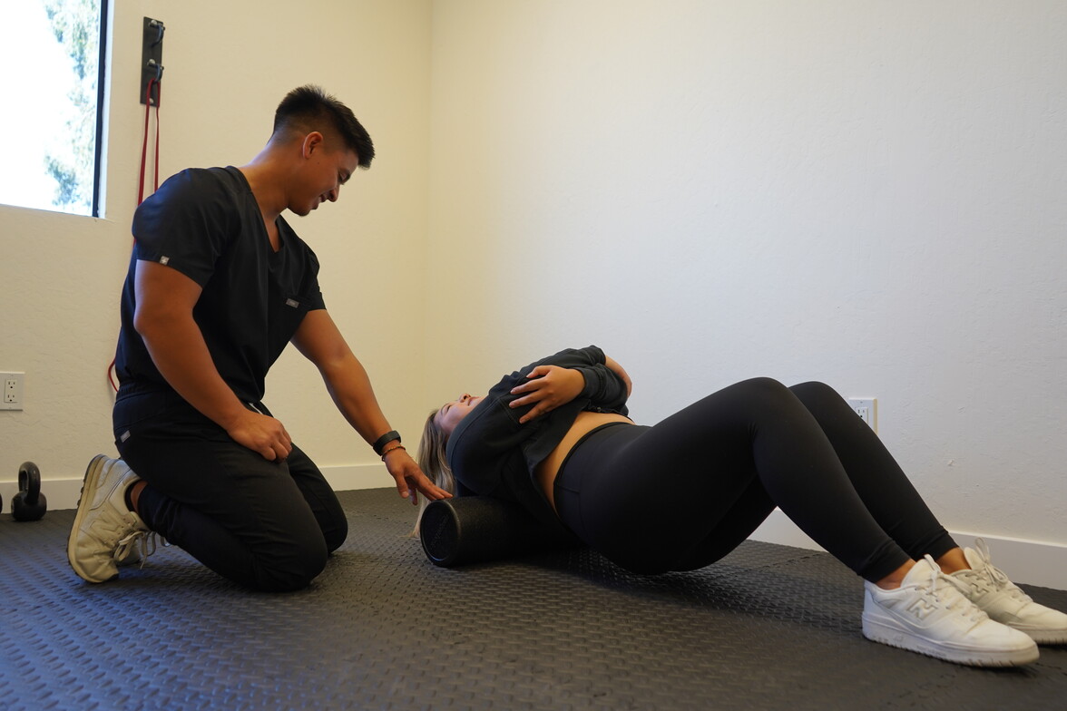 Dr. Cagape guiding a patient through thoracic mobility work over a foam roller